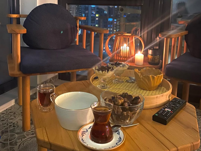 Kış balkonunda ahşap koltuk, çay bardakları ve ikramlarla dolu sehpa