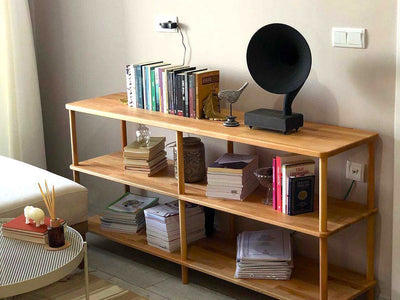 Alçak ahşap kitaplığın üzerinde gramofon, kitaplar ve dergiler