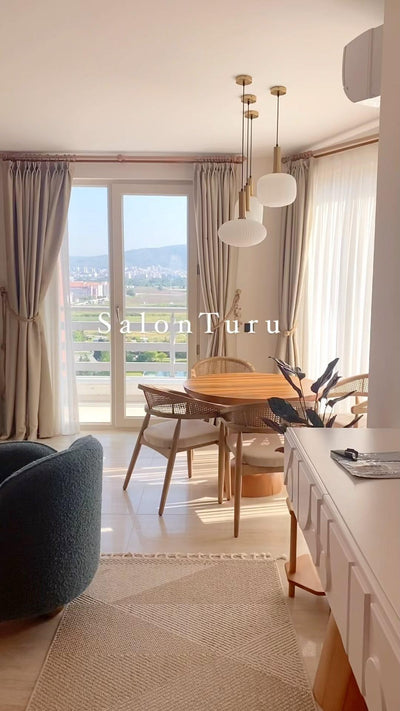 Balkon kapısının önünde ahşap yuvarlak yemek masası ve ahşap sandalyeler
