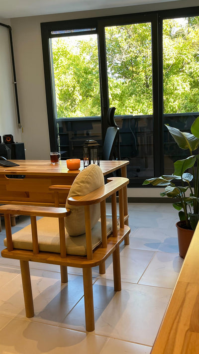 Balkon penceresi önünde ahşap yemek masası ve minderli ahşap kollu sandalye