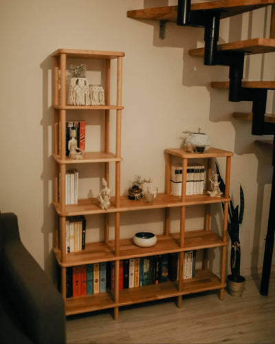 Kurulumu tamamlanmış kademeli ahşap kitaplık; raflarda kitaplar ve dekoratif objeler