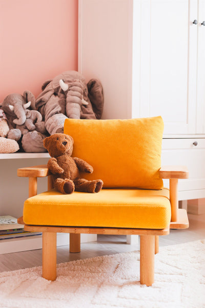 Hardal sarısı minderli ahşap çocuk koltuğunda oturan kahverengi peluş ayı