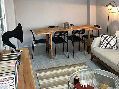 Salonda siyah sandalyelerle kullanılan uzun ahşap yemek masası