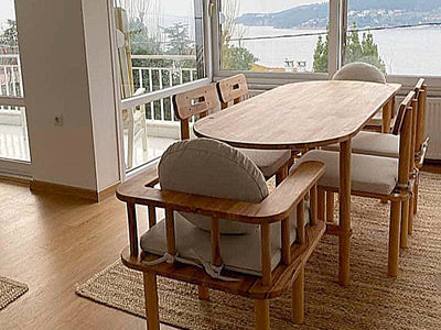 Deniz manzaralı salonda oval yemek masası, sandalyeler ve bench